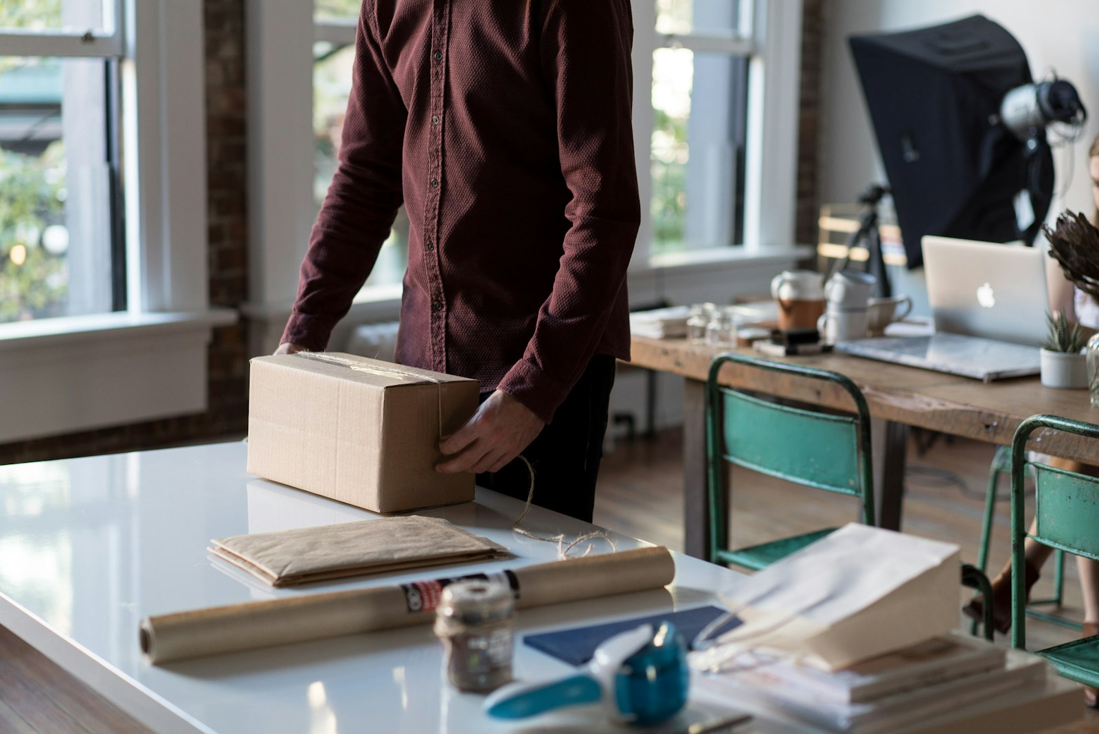 Seseorang menyiapkan kotak paket di atas meja untuk barang yang akan dijual online